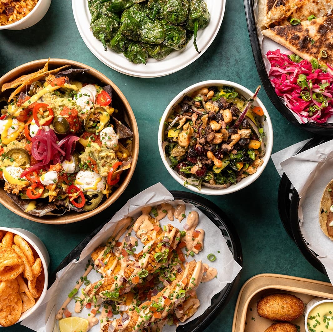 Colorful dishes featuring nachos, salads, and grilled items, surrounded by vibrant garnishes and a lively dining atmosphere.
