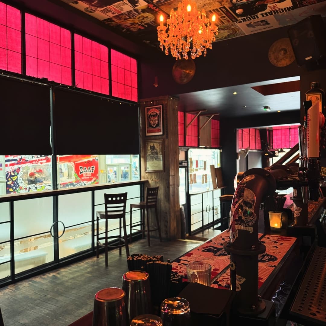 Stylish bar interior with red curtains, wooden accents, and a chandelier, creating a vibrant, inviting atmosphere.