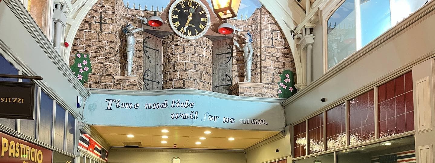 Historic market hall with a large clock, colorful murals, and vibrant shops, creating a lively dining atmosphere.