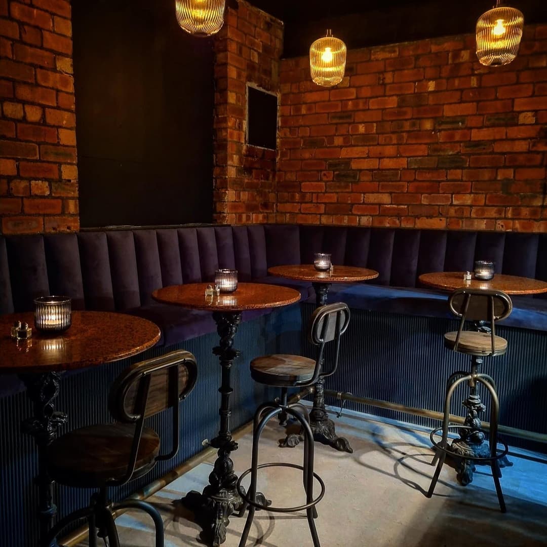 Cozy cafe interior with exposed brick walls, plush seating, and dim lighting from stylish pendant lamps.