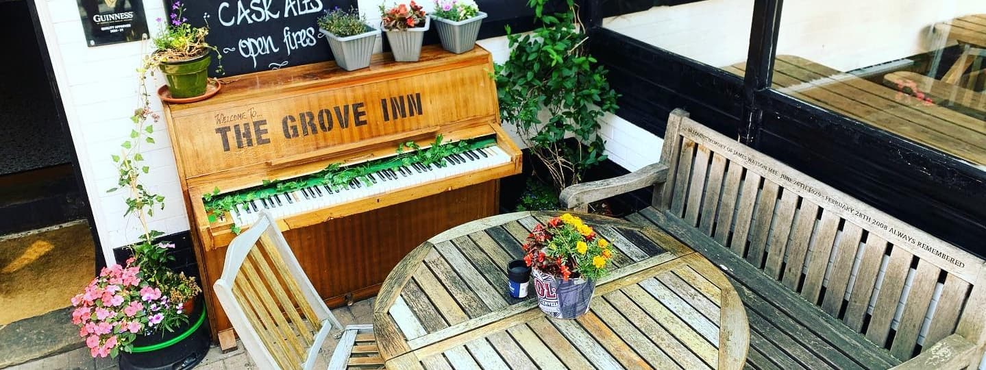 Charming outdoor seating at The Grove Inn, featuring a vintage piano and vibrant potted plants, creating a cozy atmosphere.