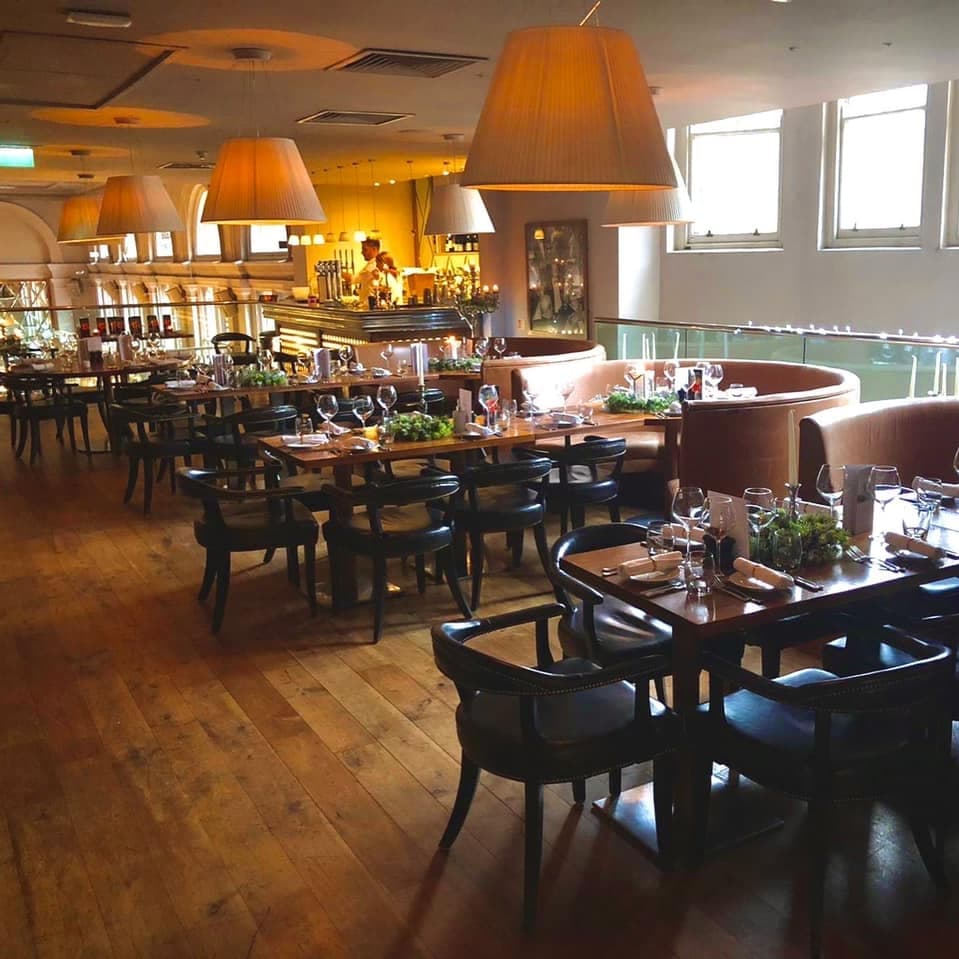 Elegant dining area with wooden floors, stylish chairs, and soft lighting, creating a warm, inviting atmosphere.