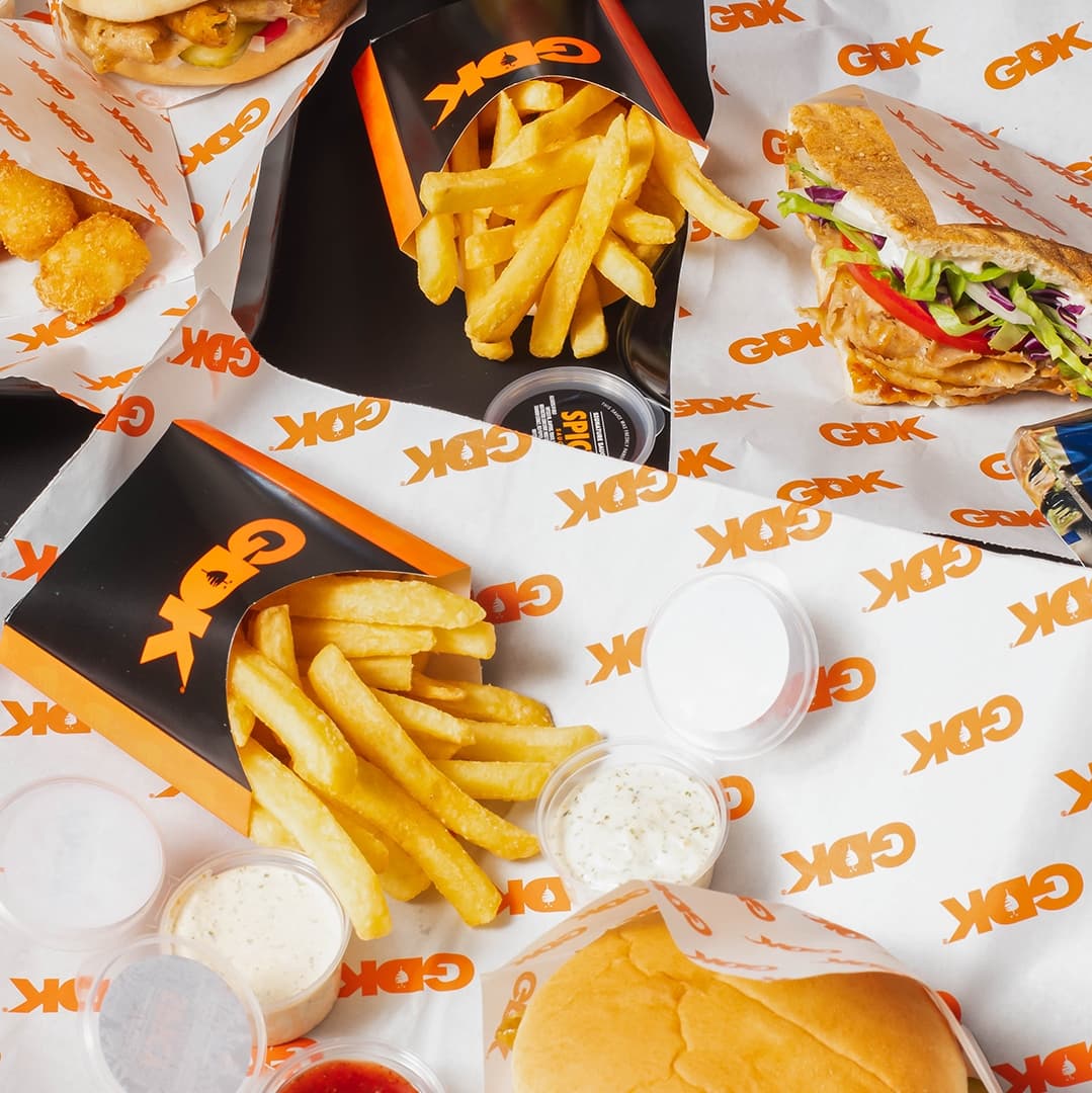 A vibrant spread of German Doner Kebab dishes, featuring fries, sauces, and a kebab wrap, all on branded paper.