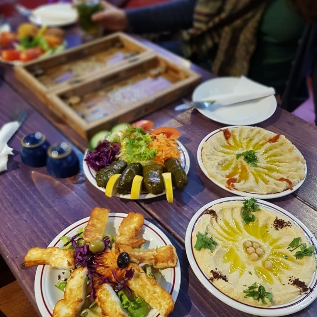 A vibrant spread of Middle Eastern dishes, including hummus, salad, and grilled cheese, on a wooden table.