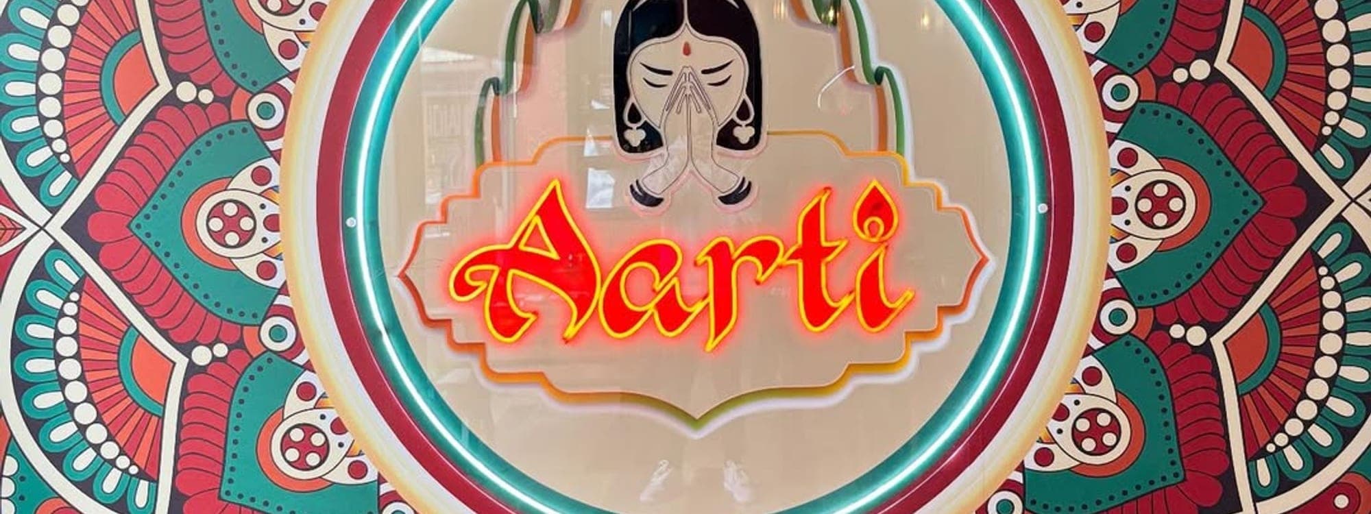 Aarti Indian Restaurant neon sign at the centre of a vibrant red and teal mandala mural