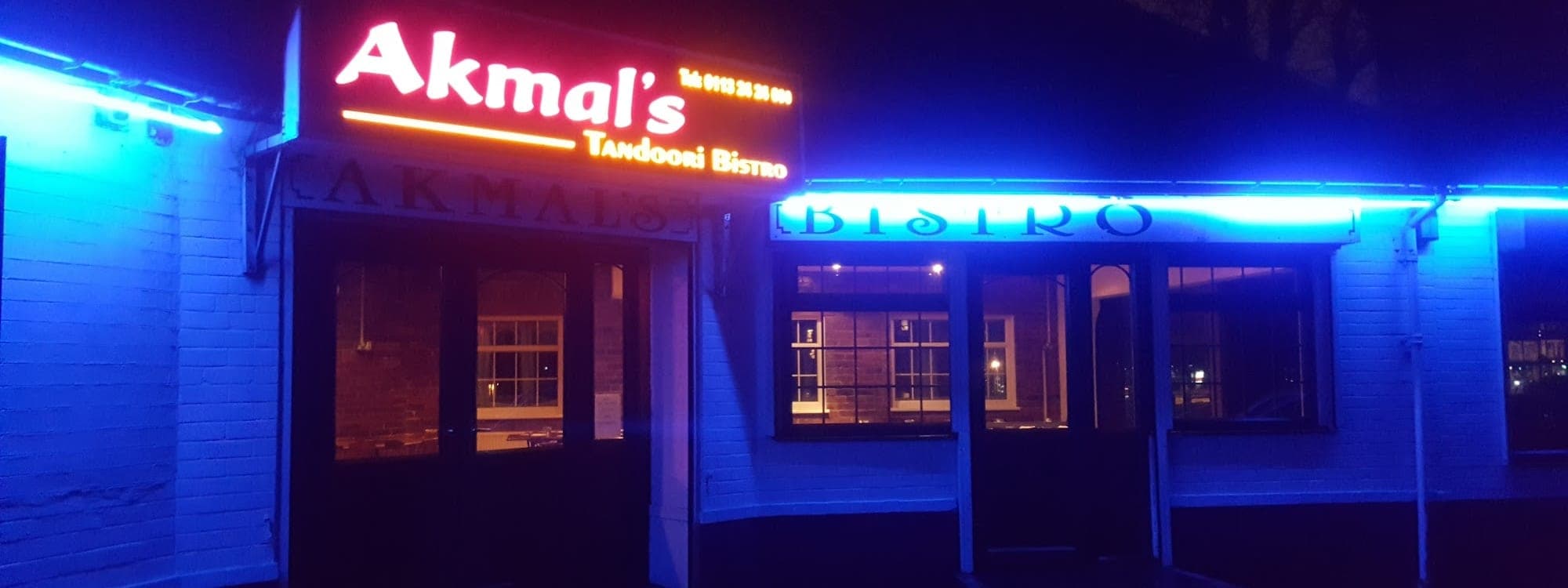 Akmal's Tandoori Bistro — exterior at night with neon sign