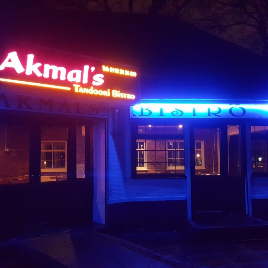 Akmal's Tandoori Bistro — exterior facade at night with neon sign