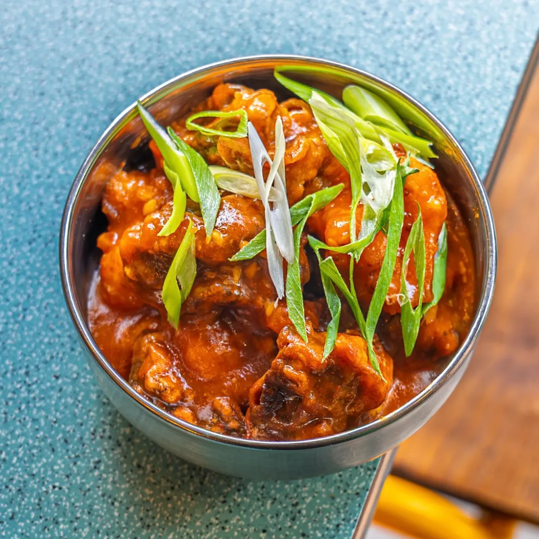 Bundobust gobi manchurian in steel bowl garnished with spring onions