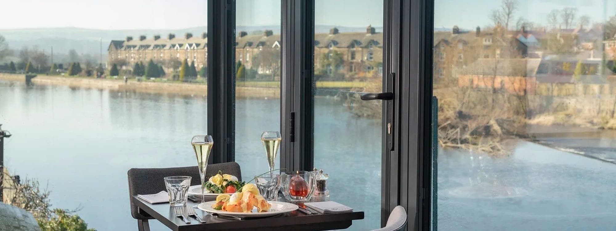 Buon Apps River Lounge — dining table set with champagne overlooking the River Wharfe through floor-to-ceiling windows