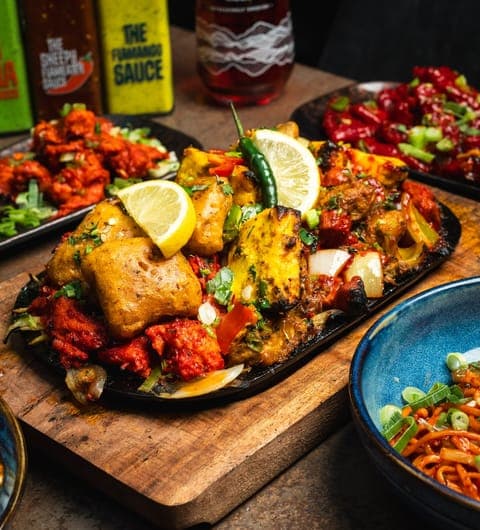 Colourful mixed grill sizzler platter with tandoori chicken, seekh kebab, and house sauces at Sheepscar Bar and Grill