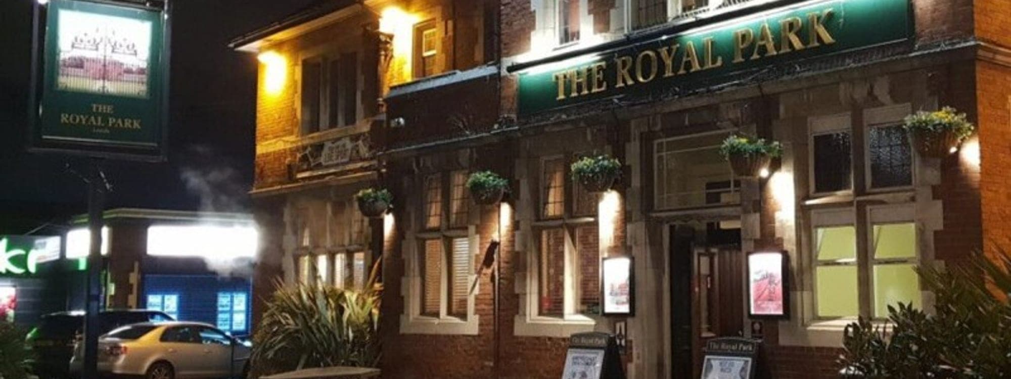 The Royal Park pub in Leeds lit up at night with warm lighting and outdoor benches