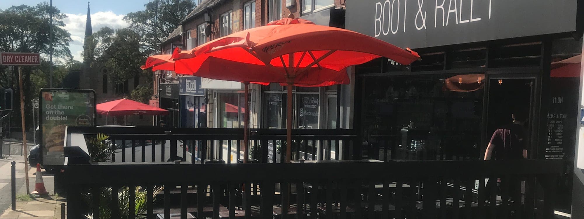 Exterior of Boot and Rally bar in Meanwood Leeds with red parasols and outdoor seating terrace