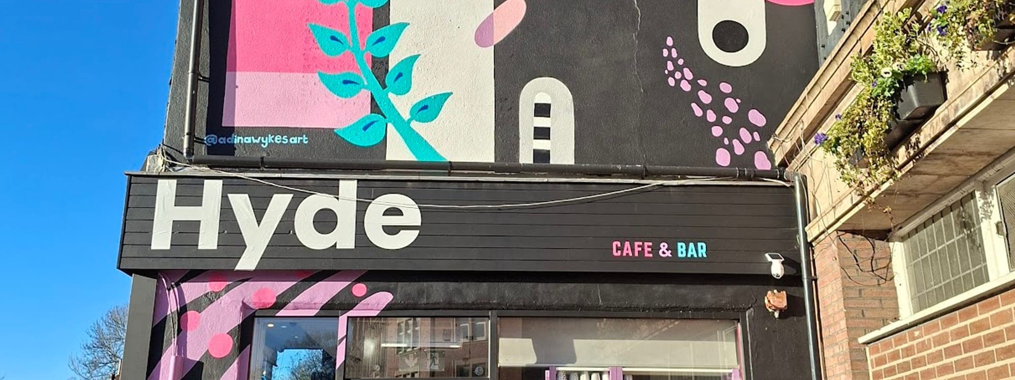 Colourful exterior of Hyde Cafe and Bar on Headingley Lane Leeds with bird mural and outdoor seating