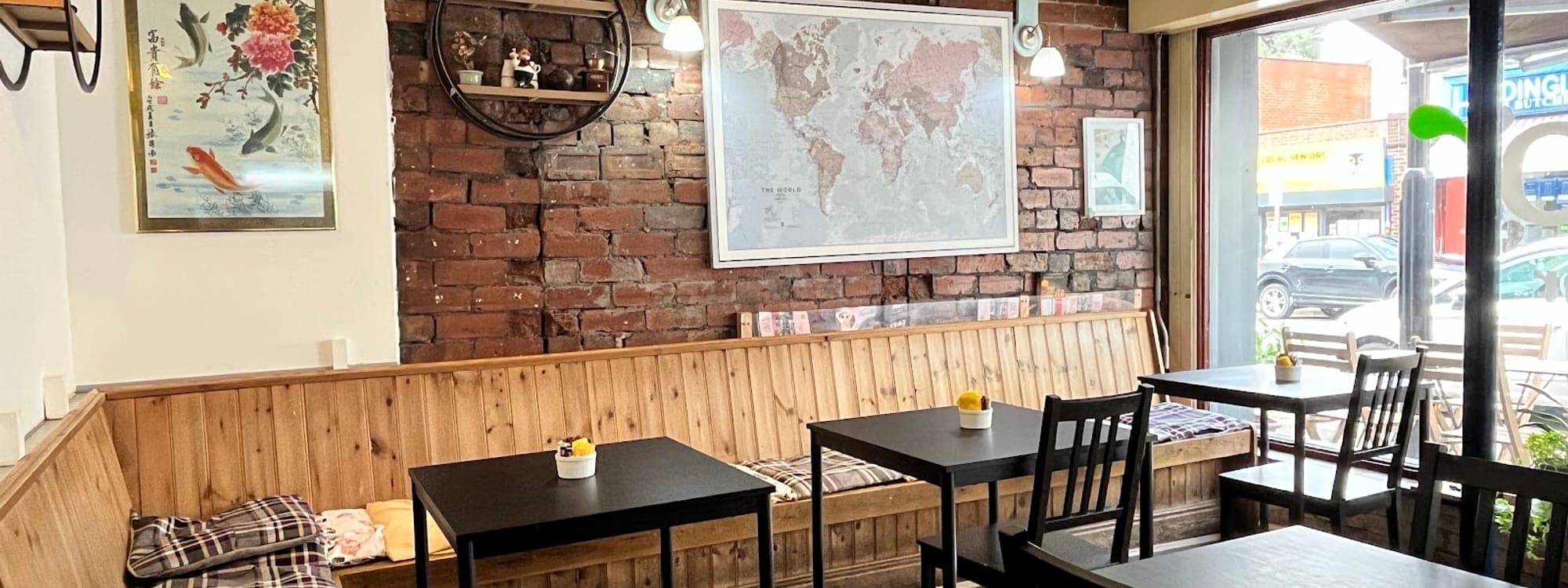 Interior of Lento Cafe and Bar in Headingley with exposed brick walls, world map, and cosy wooden seating