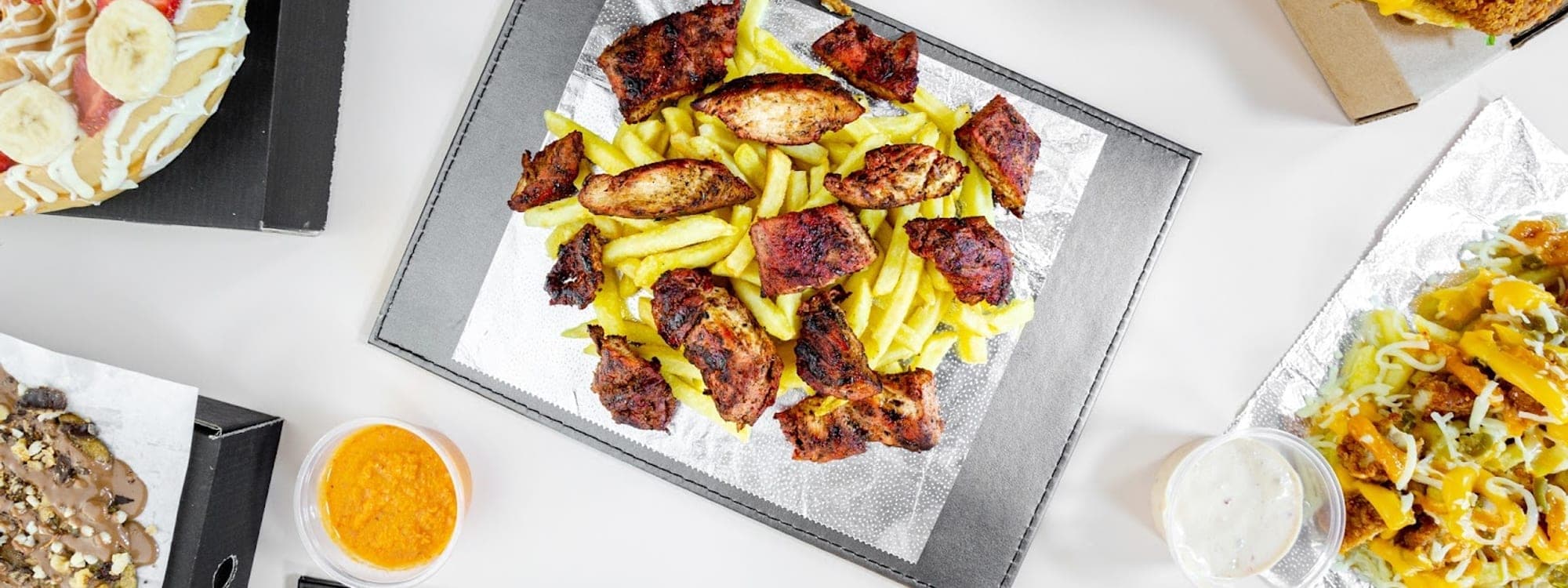 FiveStar burgers and shakes — overhead flat-lay spread of burgers, loaded fries, waffle and wings