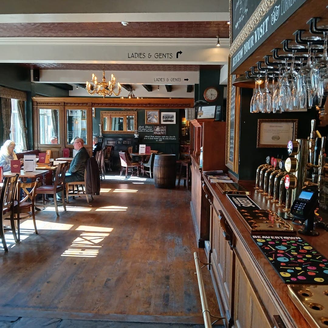 The Scarbrough Hotel — sunlit bar area with wooden floors, cask ale taps, and traditional pub furniture