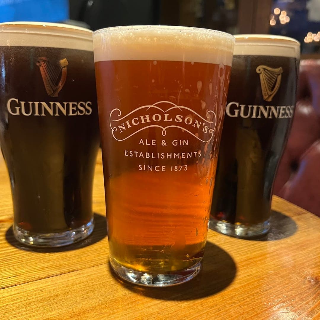The Scarbrough Hotel — two pints of Guinness and a Nicholsons ale on a leather-backed table