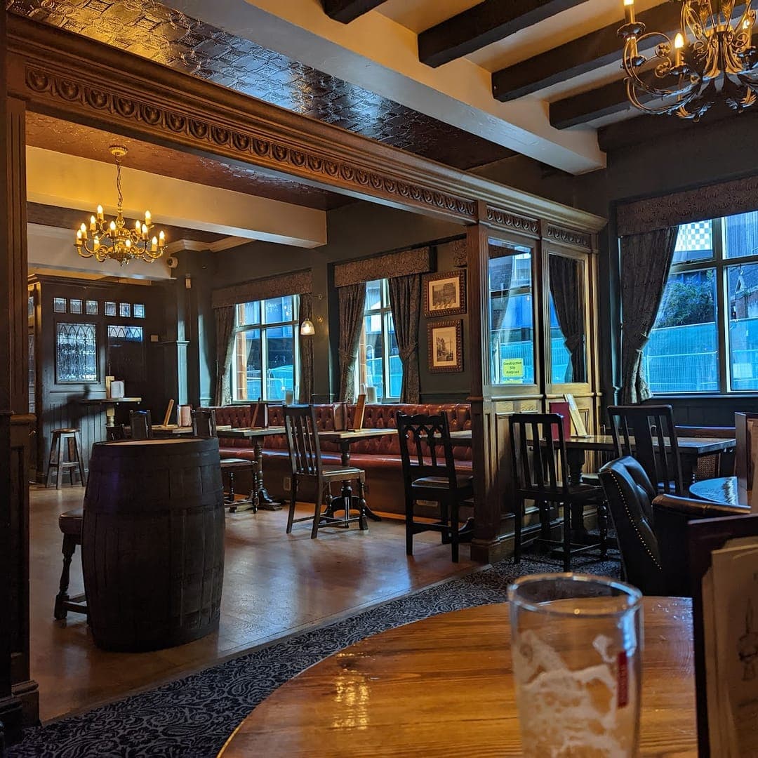 The Scarbrough Hotel — atmospheric interior with chandeliers, dark wood panelling, and barrel table