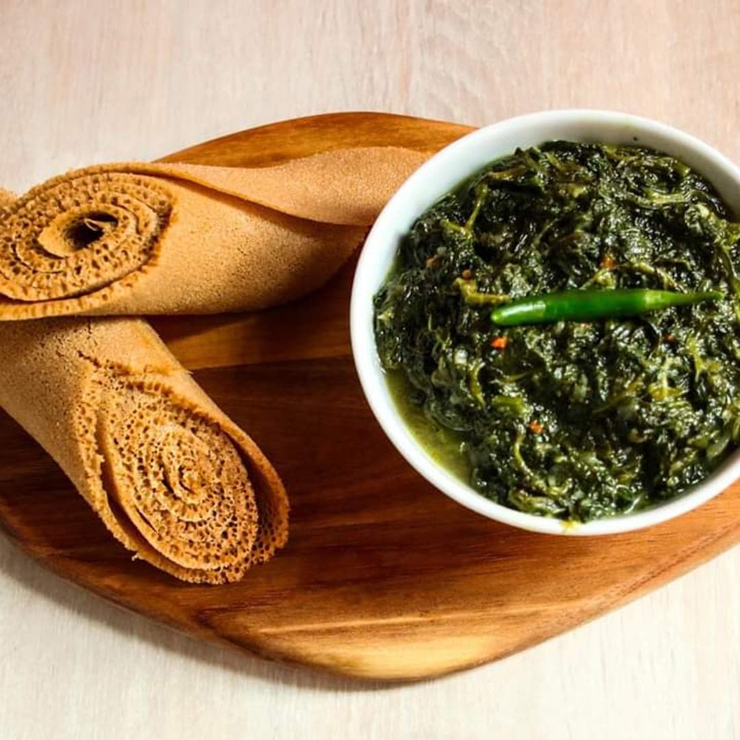 Gomen and rolled injera served on a wooden board at Abashawel Restaurant