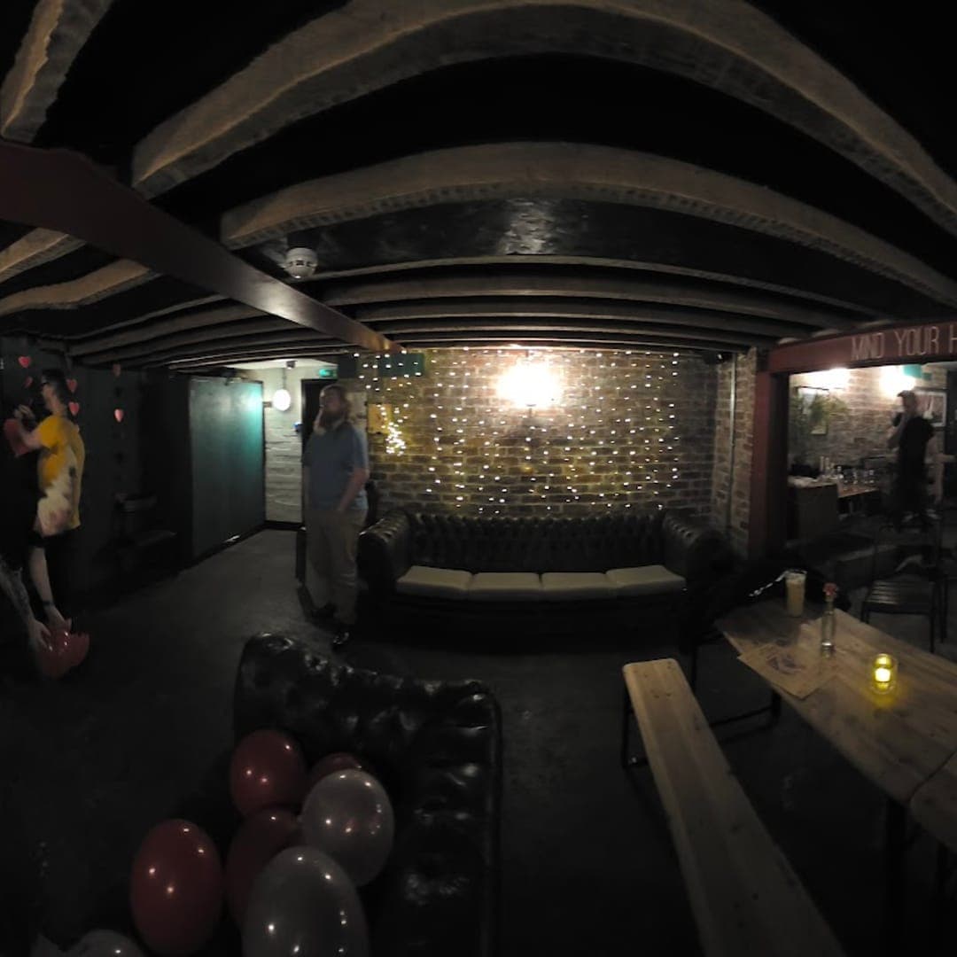 Basement bar at Boot and Rally with exposed beams, fairy lights, and leather sofas