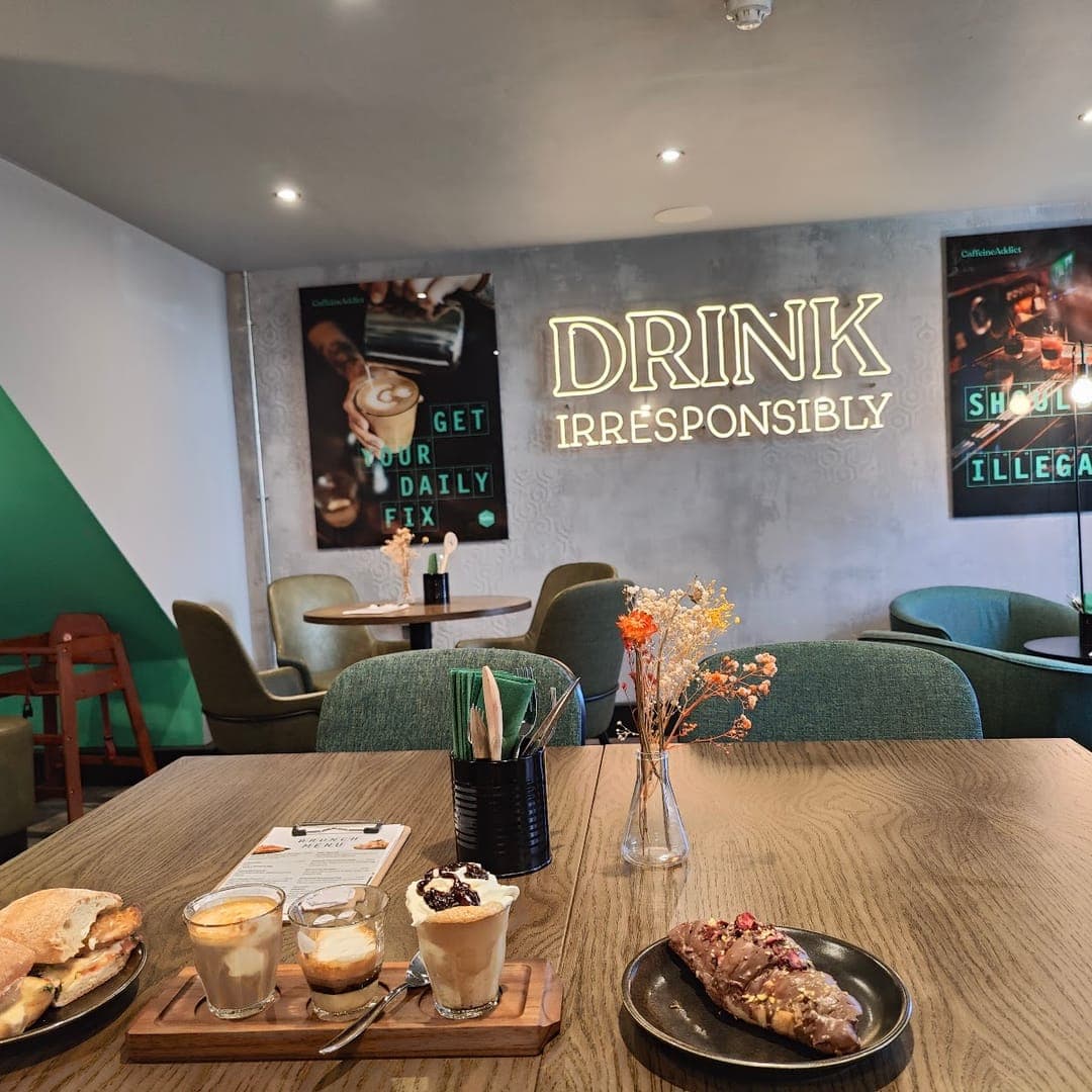 Interior of Caffeine Addict with green seating, wall art, and brunch spread on table
