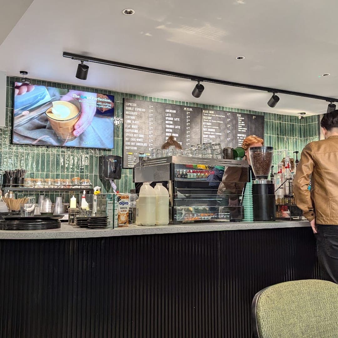 Counter area at Caffeine Addict with coffee machine, menu board, and customers ordering