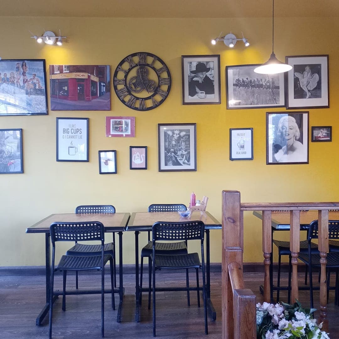 Interior of Chichini cafe with yellow walls, vintage framed photos, and black seating