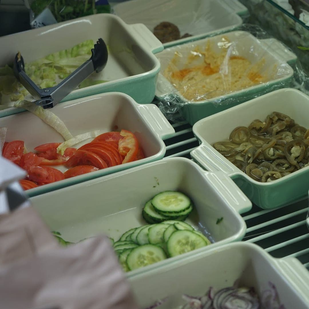 Fresh salad bar close-up with tomatoes, olives, cucumber, and coleslaw at Chichini