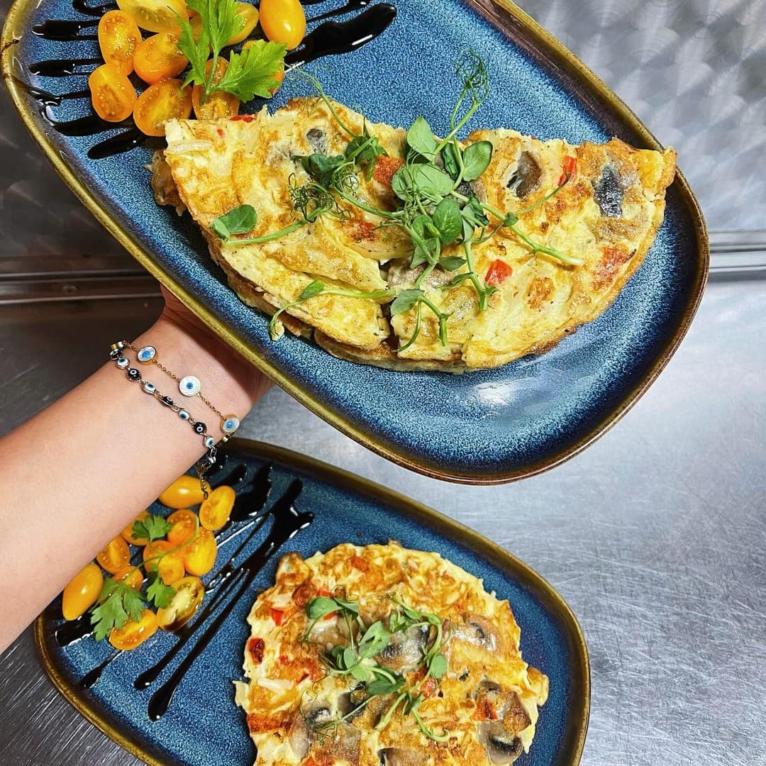 Herb omelette with cherry tomatoes served on a blue plate at Country Crust Leeds