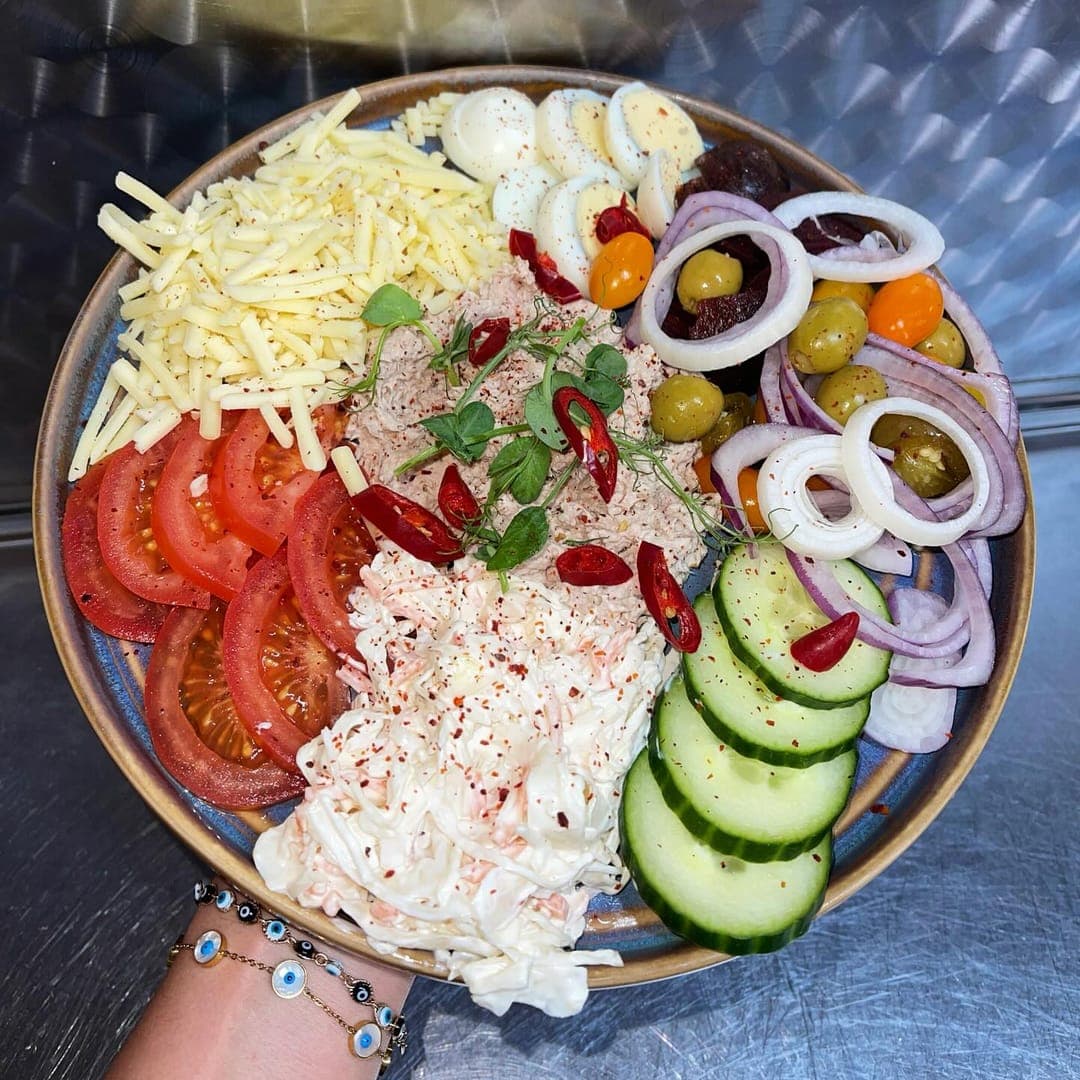Loaded salad bowl with tomatoes, cucumber, olives, cheese, and onion at Country Crust