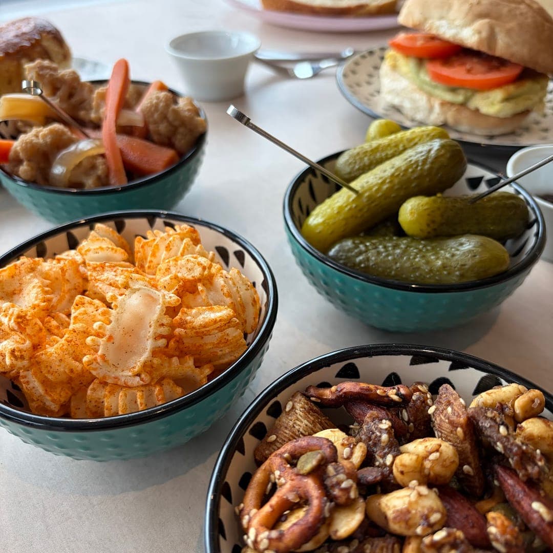 Snack bowls with crisps, gherkins, and mixed nuts with a burger at Hyde Leeds