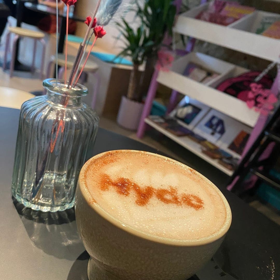 Latte with Hyde branded art in a ceramic cup with dried flowers at Hyde Cafe