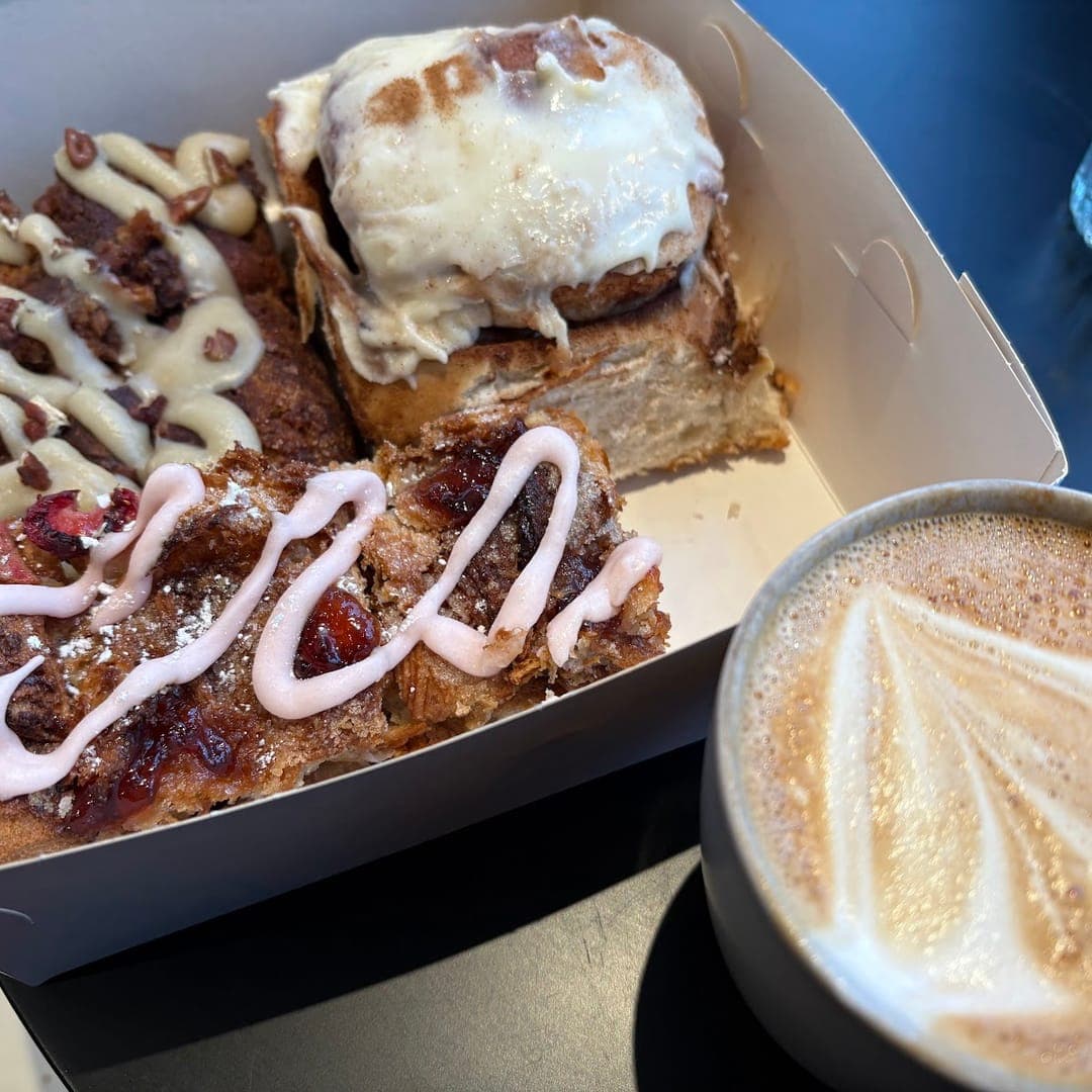 Box of brownies and cake slices with a latte art coffee at Hyde Cafe Leeds