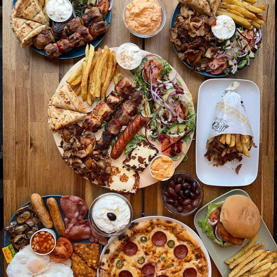 Overhead view of Greek platters, pizza, burger, and eggs at Mistreci Leeds