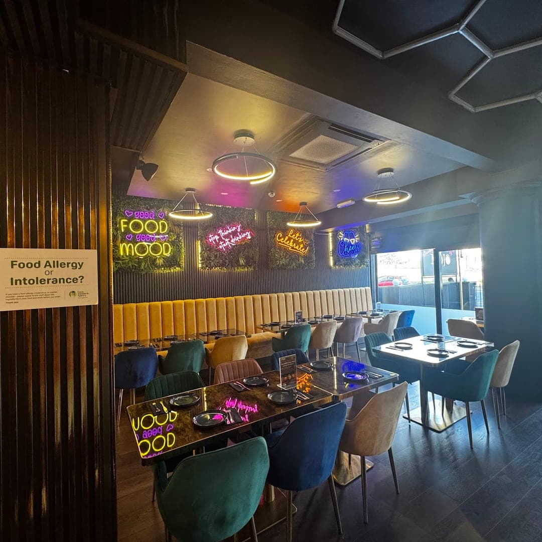Interior of Mojo Royal Treat with neon Food is my Mood signs and colourful velvet seating