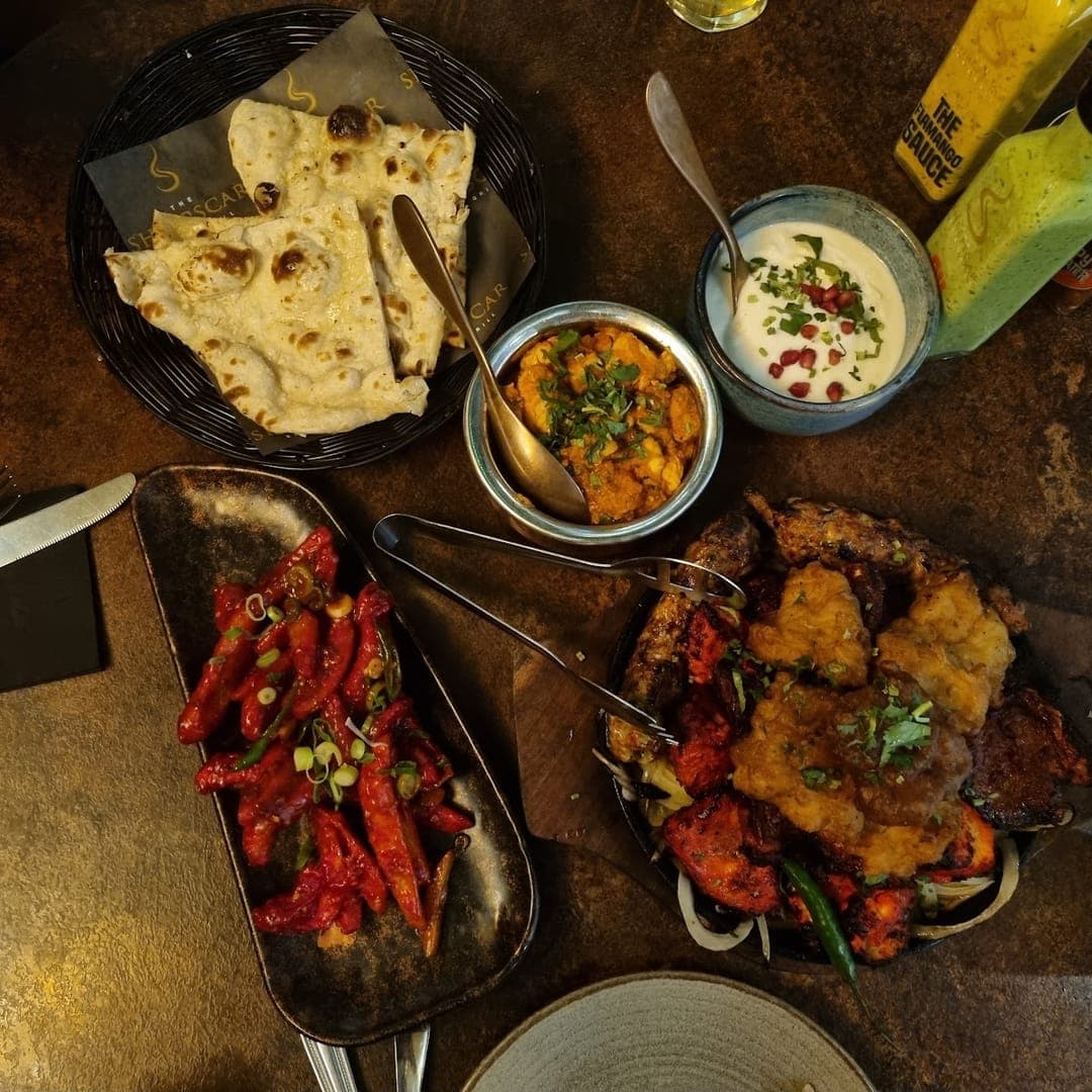 Overhead view of naan bread, curries, and mixed starters at Sheepscar Bar and Grill