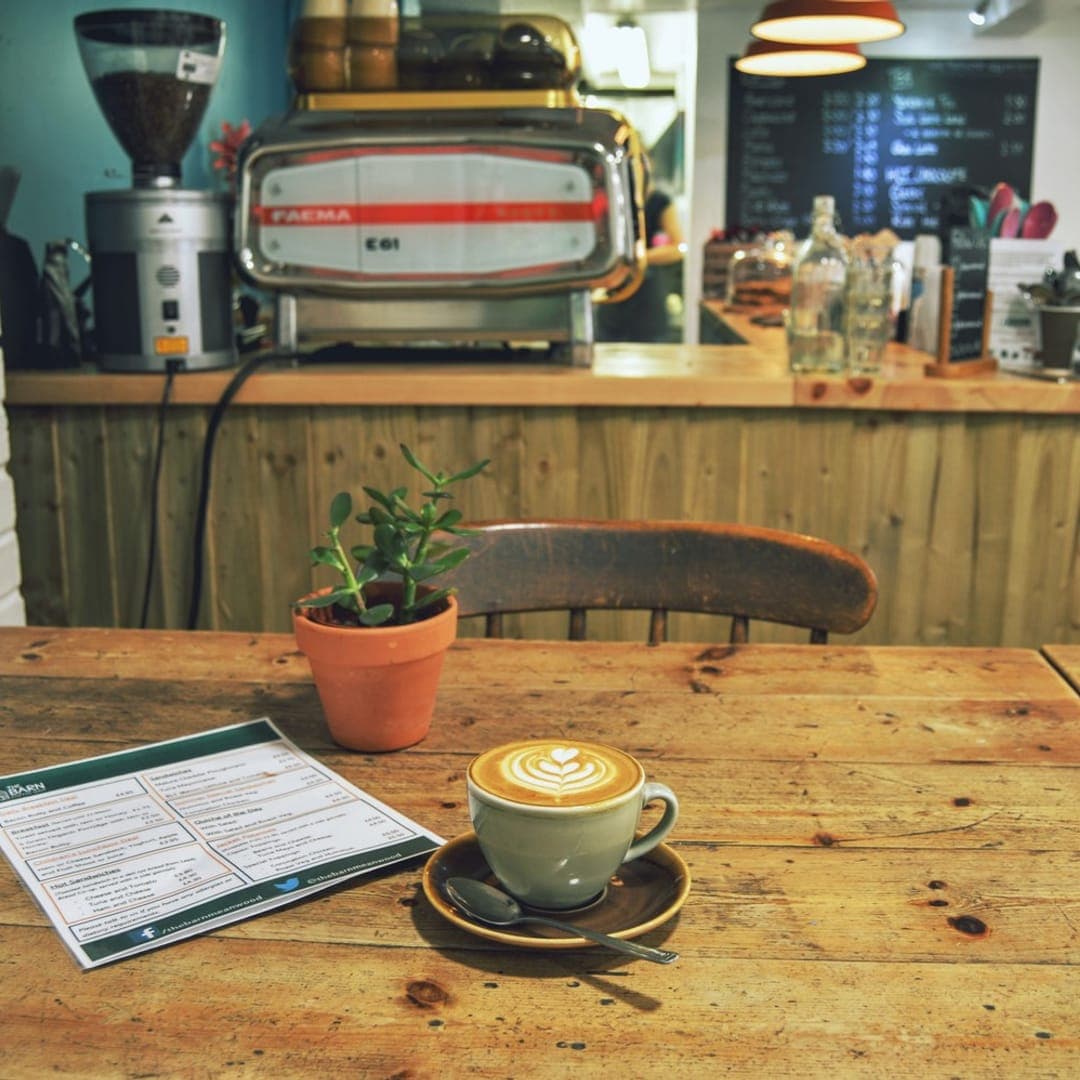 Latte art coffee with menu on a rustic wooden table at The Barn Coffee Shop Meanwood
