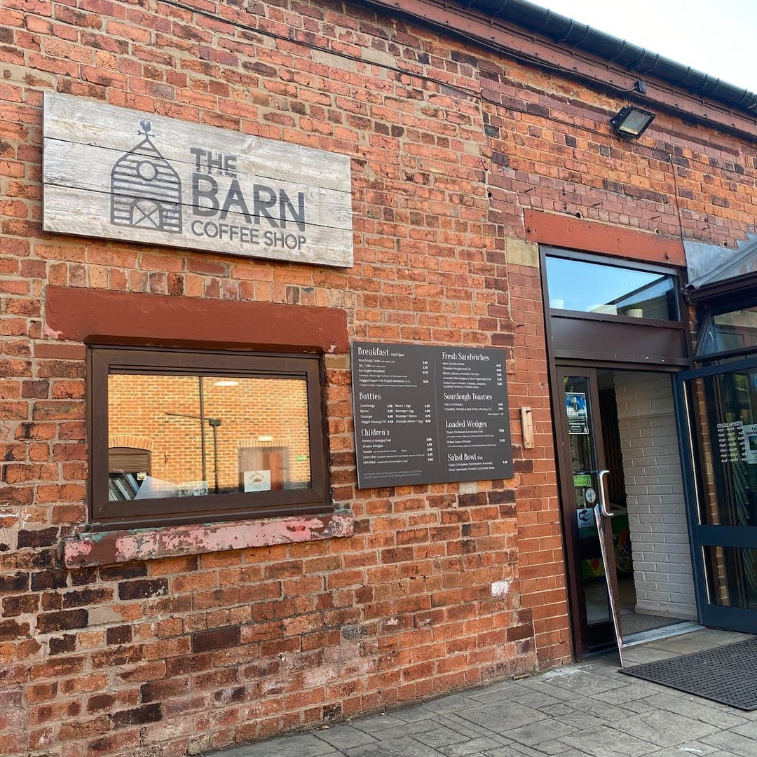 Brick exterior of The Barn Coffee Shop with signage and glass doors at Meanwood Valley Urban Farm