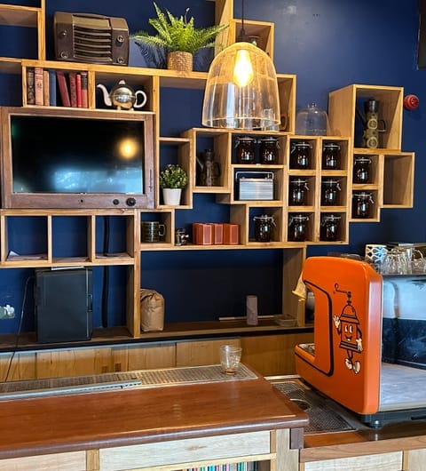 Grounded & Co — orange espresso machine with distinctive coffee grinder mascot at the bar