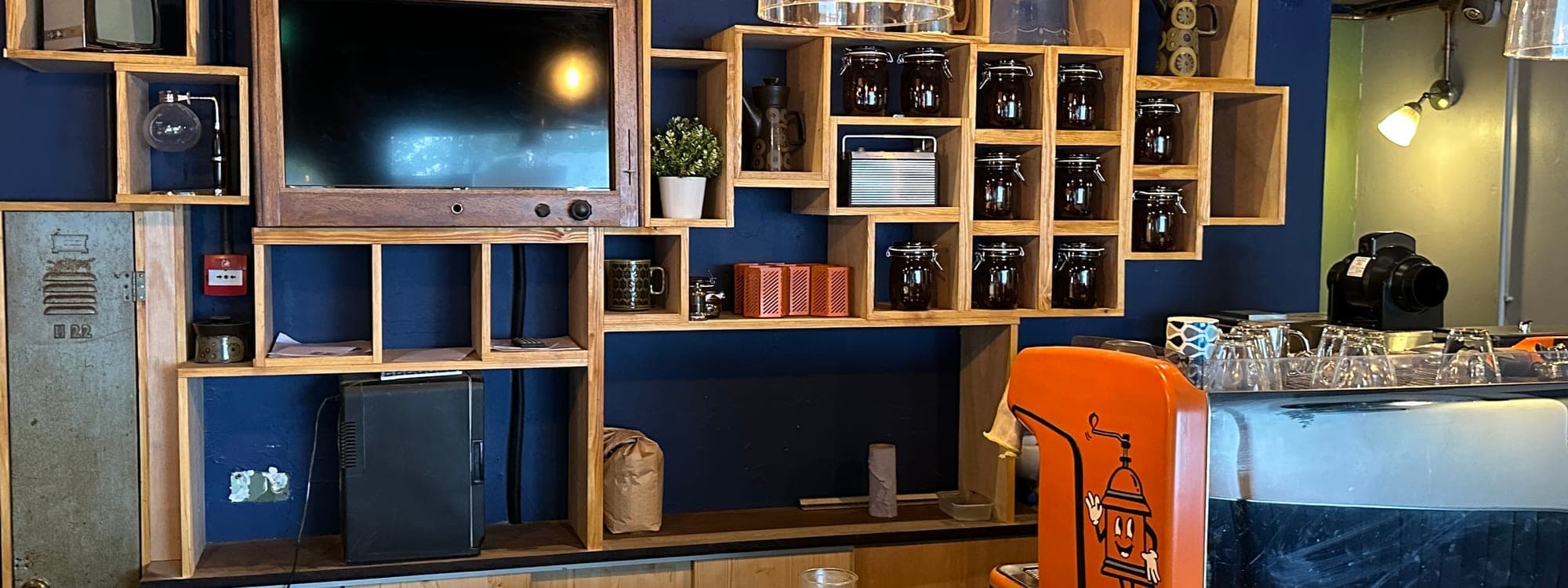 Grounded & Co — interior bar with orange espresso machine, wooden shelving and blue walls