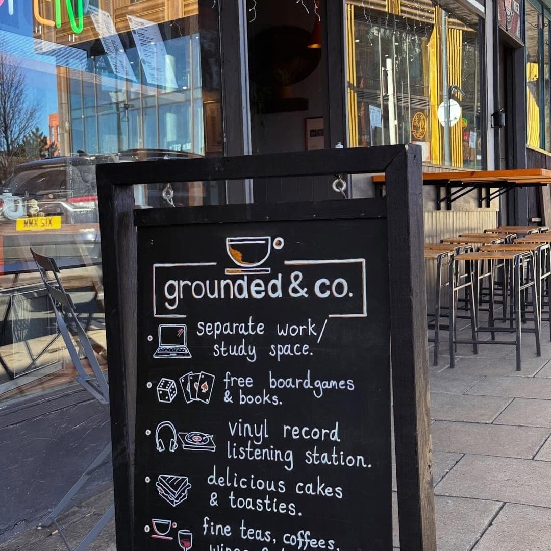 Grounded & Co — exterior with A-board sign listing venue features and outdoor seating