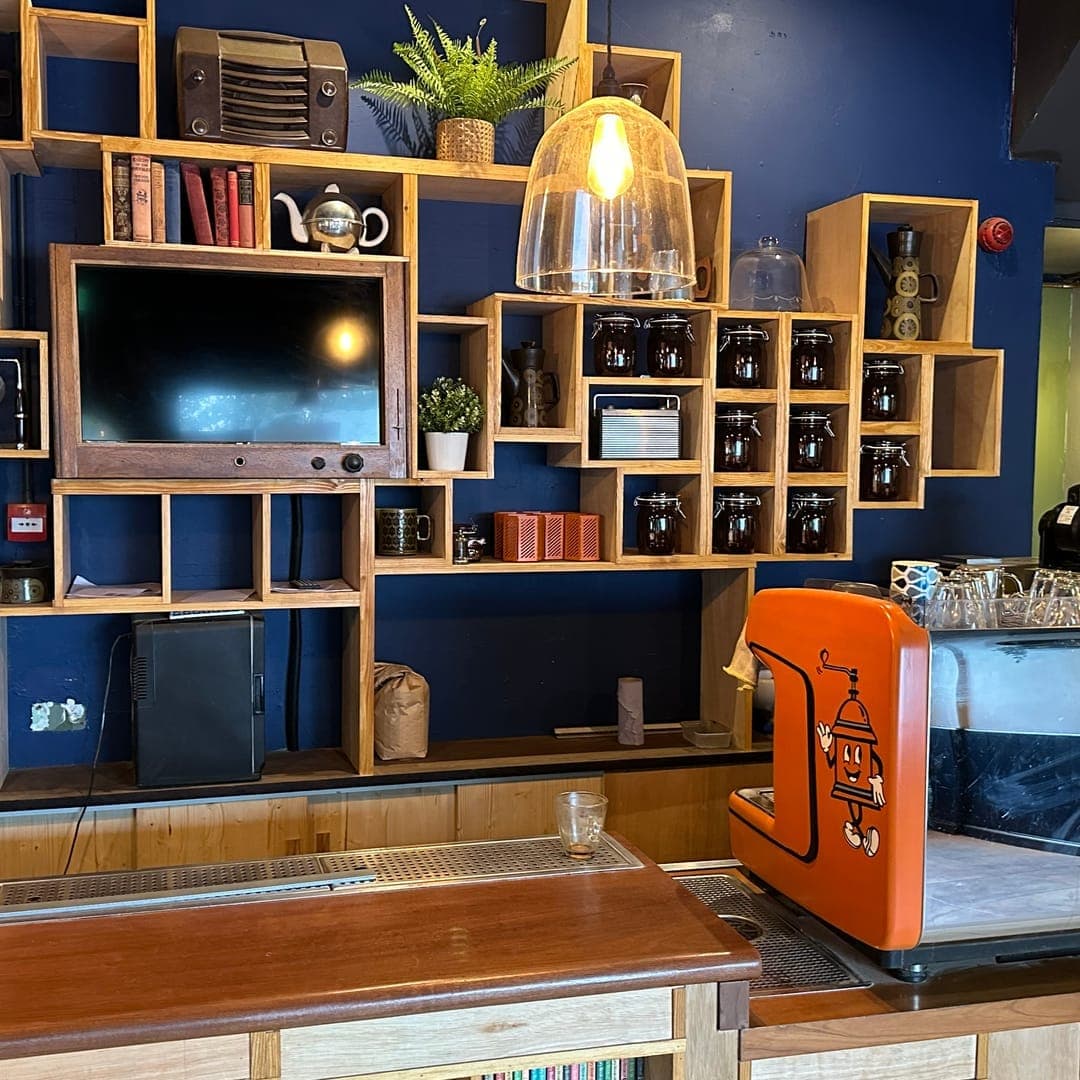 Grounded & Co — interior bar area with orange espresso machine and eclectic wooden shelving