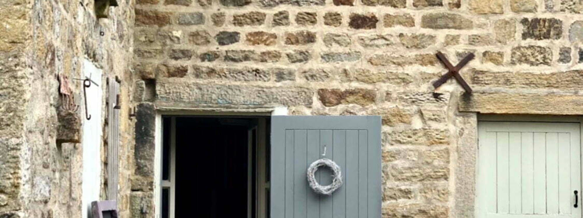 MISTÅL Kitchen — stone barn exterior with grey door and bunting
