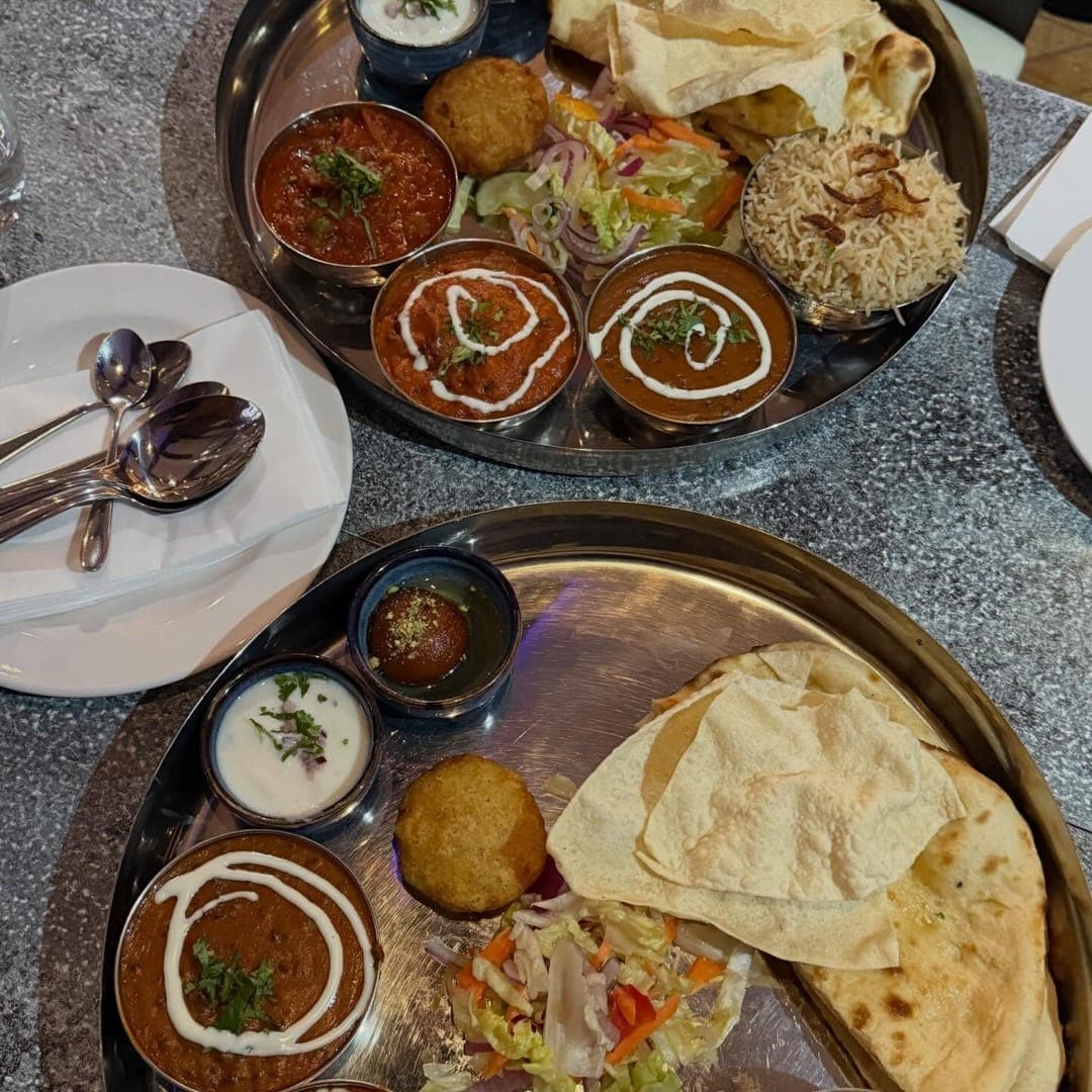 Munch Cafe English Kitchen — two steel thali trays with curries, naan and rice