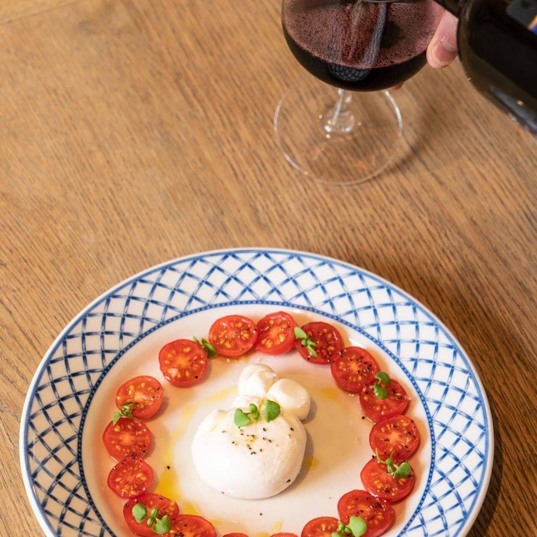 No 14 North Lane Restaurant & Bar — burrata with cherry tomatoes on blue patterned plate with red wine being poured