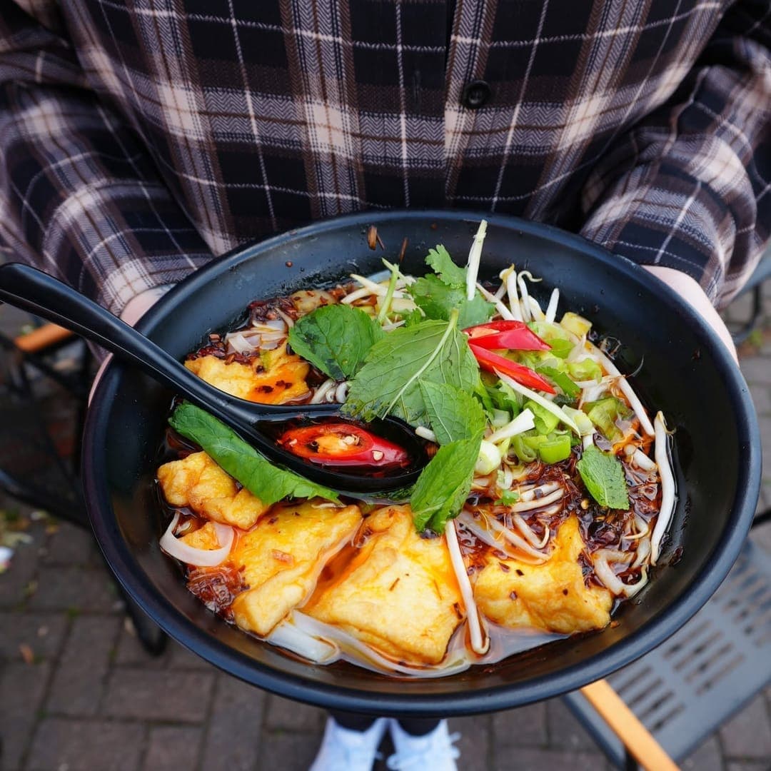 Pho 37 (Merrion Centre) — spicy noodle bowl with tofu, chili and herbs held from above