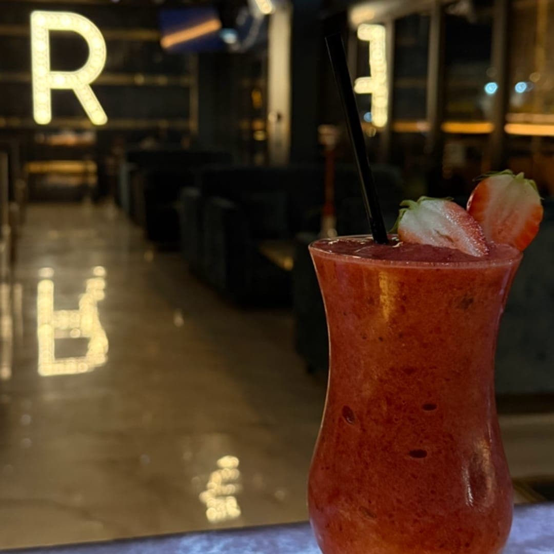 Riviera lounge — strawberry cocktail with venue interior in background