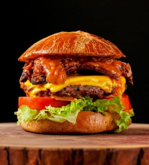 Secret Sky — towering smash burger with melted cheese and bacon on a wooden board