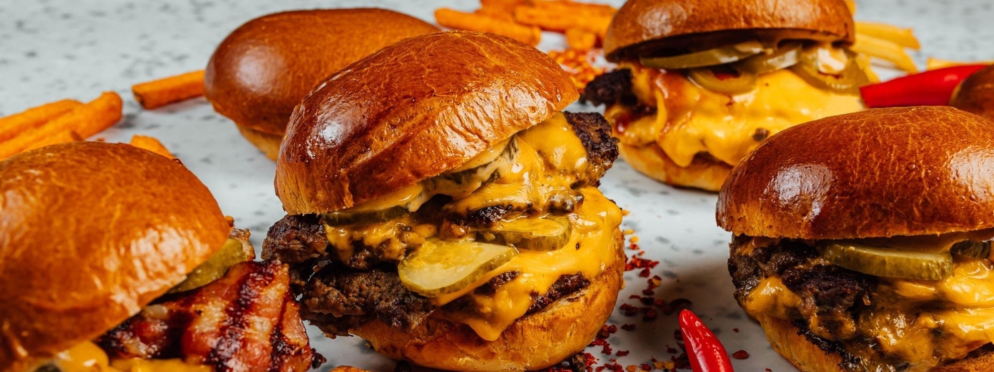Secret Sky — smash burgers and sweet potato fries spread across a marble surface