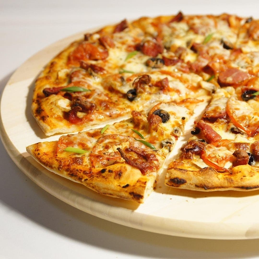 Secret Sky — loaded meat pizza sliced on a white ceramic board